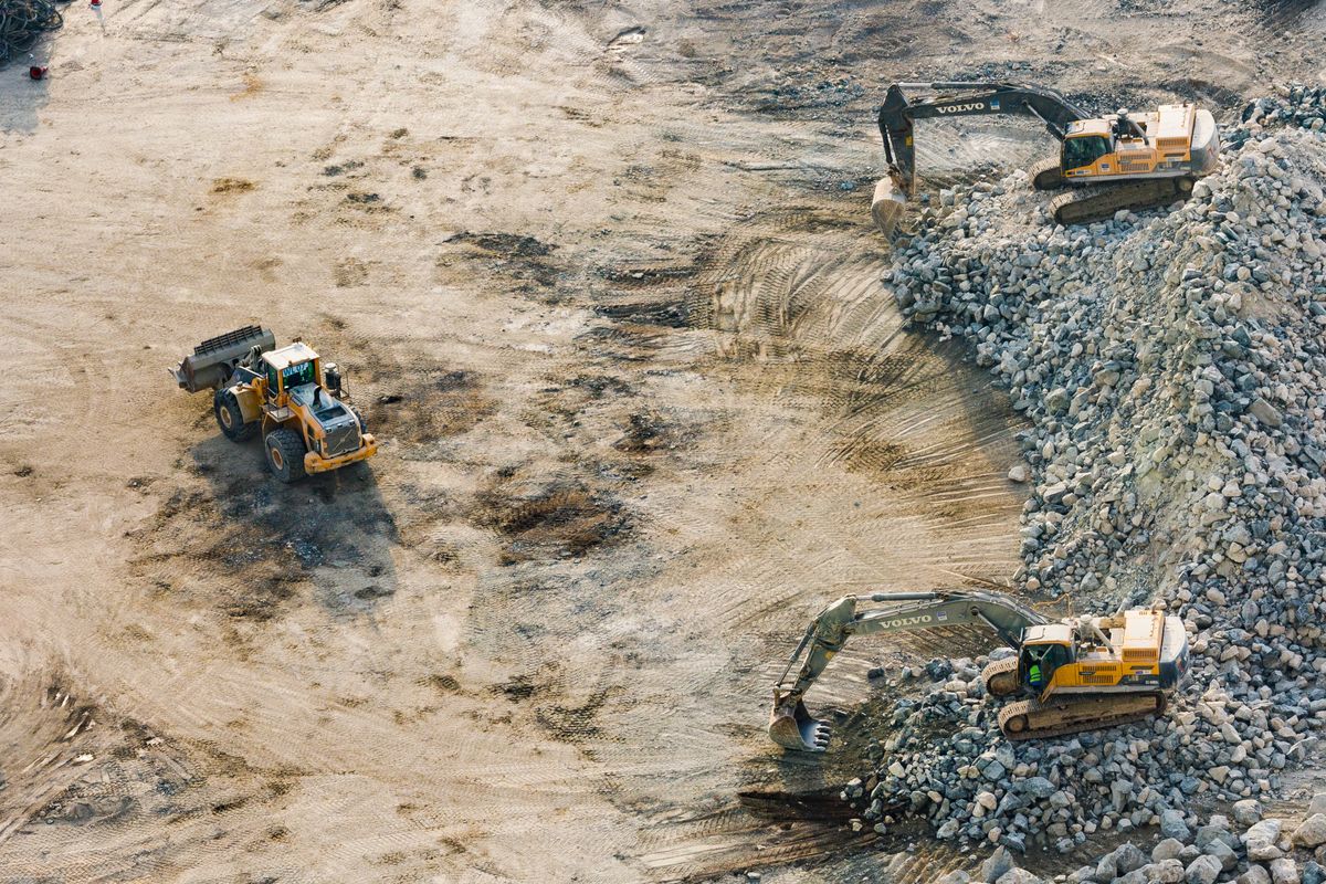 Excavator preparing ground on a construction site with crew nearby